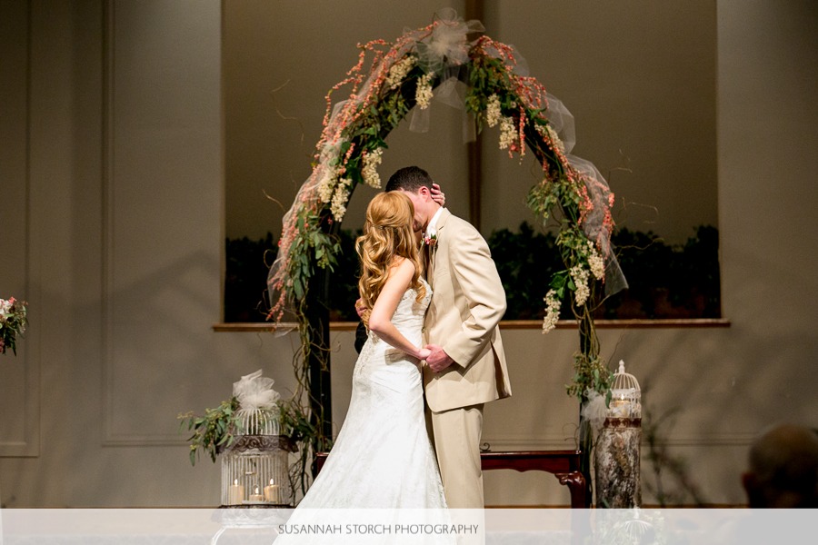 bride and groom kiss in front of an altar