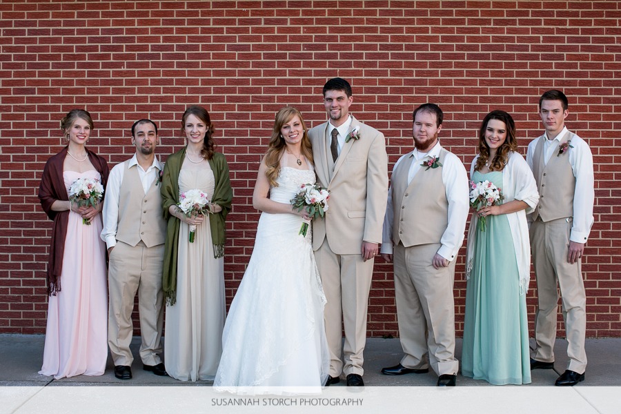 a bride and groom stand in the center of their bridesmaids and groomsmen