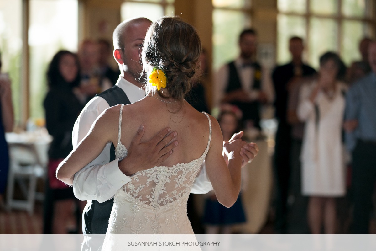 a groom places his hand on the back of his bride while they slowdance
