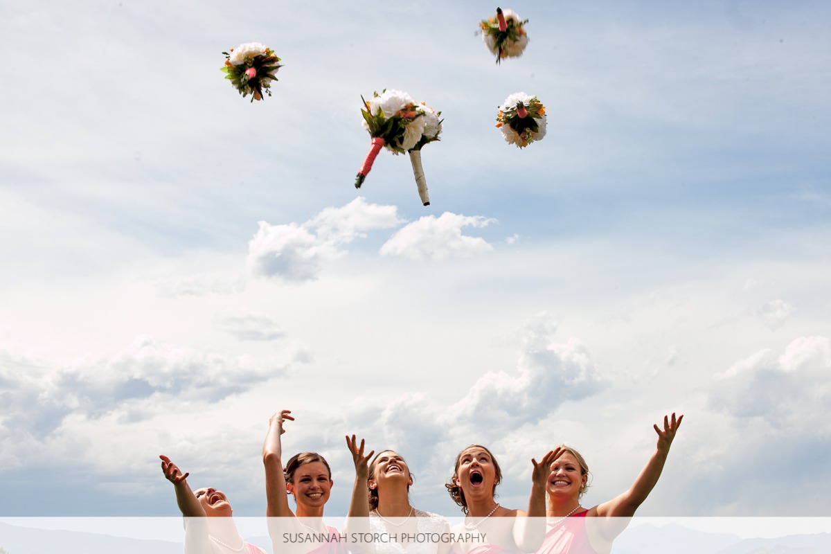 five woman toss bouquets into the air and smile
