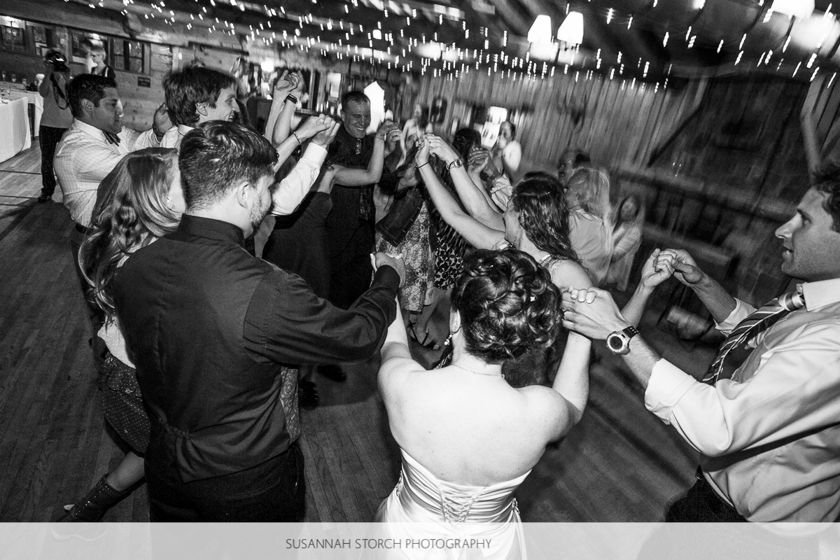 black and white photo of wedding guests holding hands and dancing