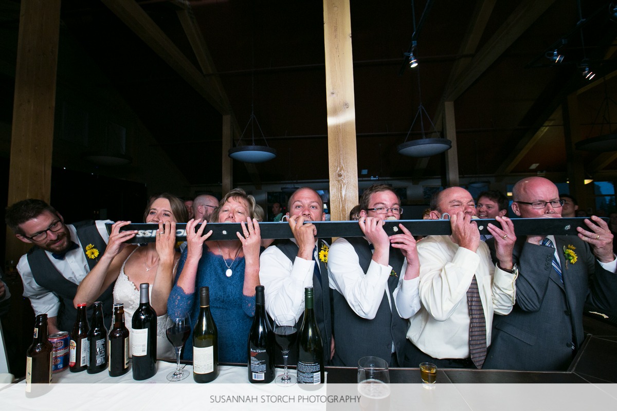 a groom looks at the camera as he and his family members take shots from a ski