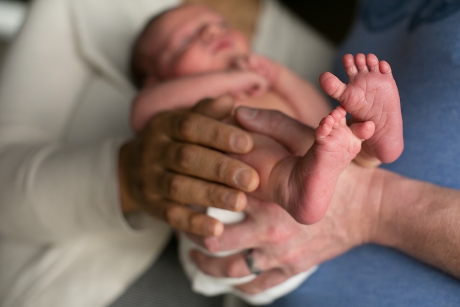 a moms hands hold her newborn son