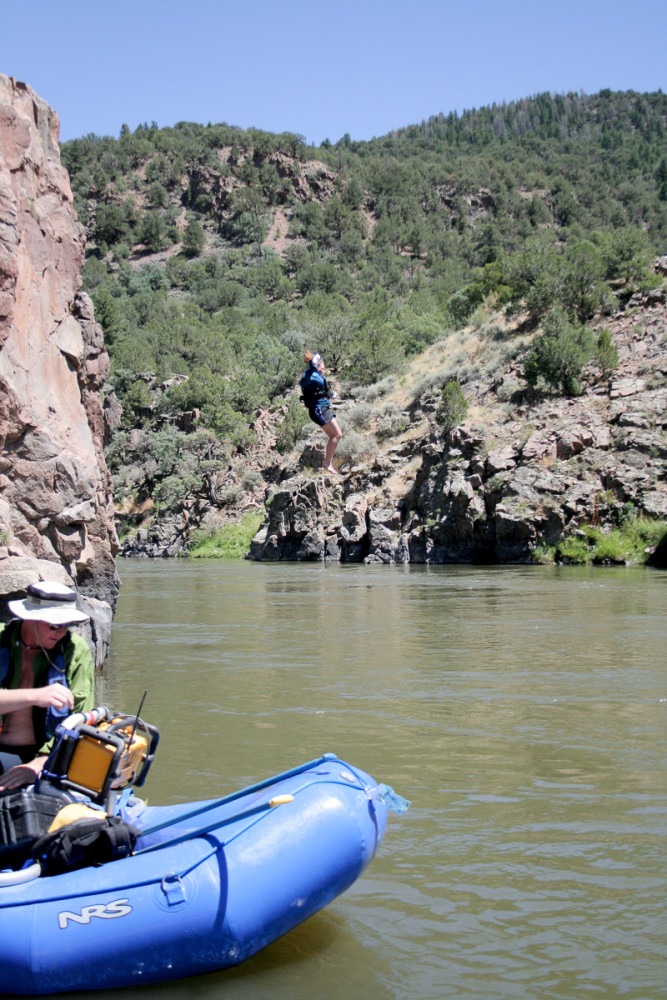 a woman in blue falls through the air into a river