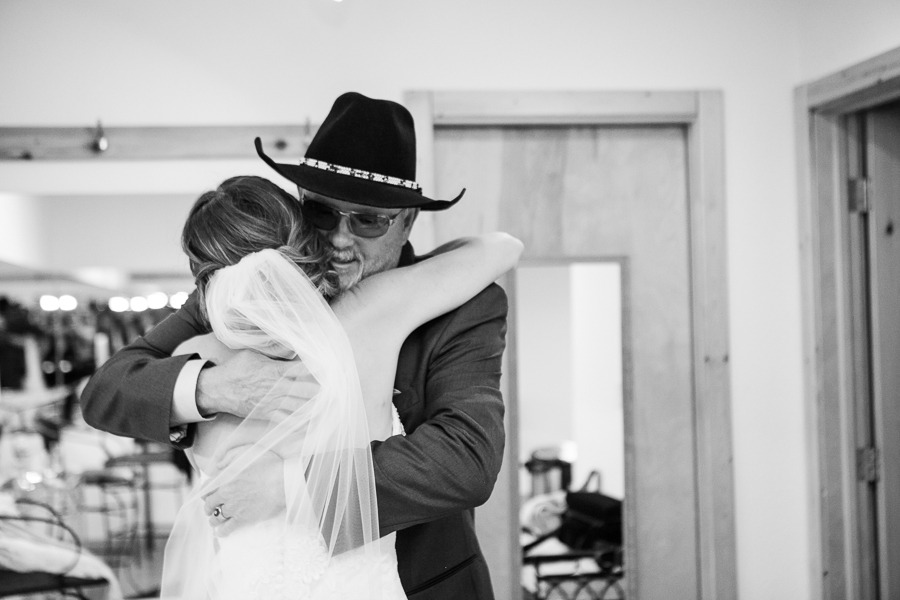 black and white of a man in a black hat hugging his daughter on her wedding day