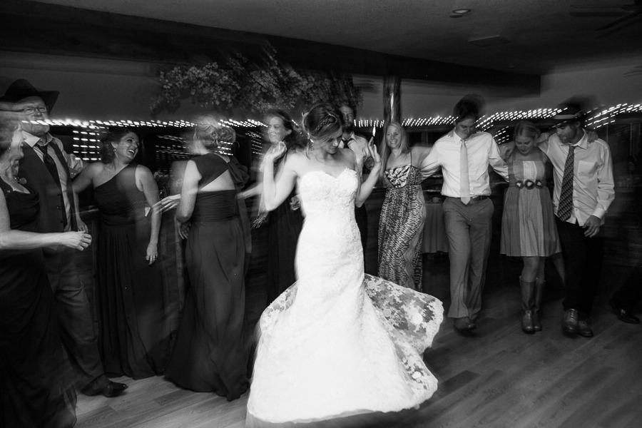 black and white long exposure photo of a wedding guests dancing a line while a bride twirls
