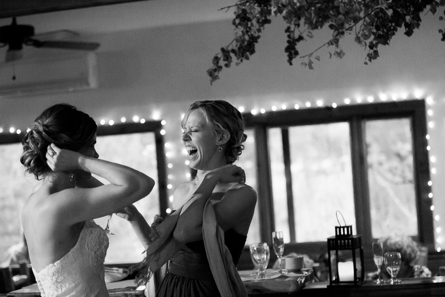black and white photo of a woman laughing heartily while talking to a bride