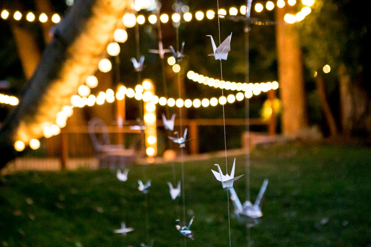 party lights hang from trees and paper cranes hang from string