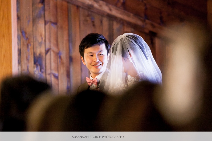 a groom in a pink bowtie looks at his veiled bride