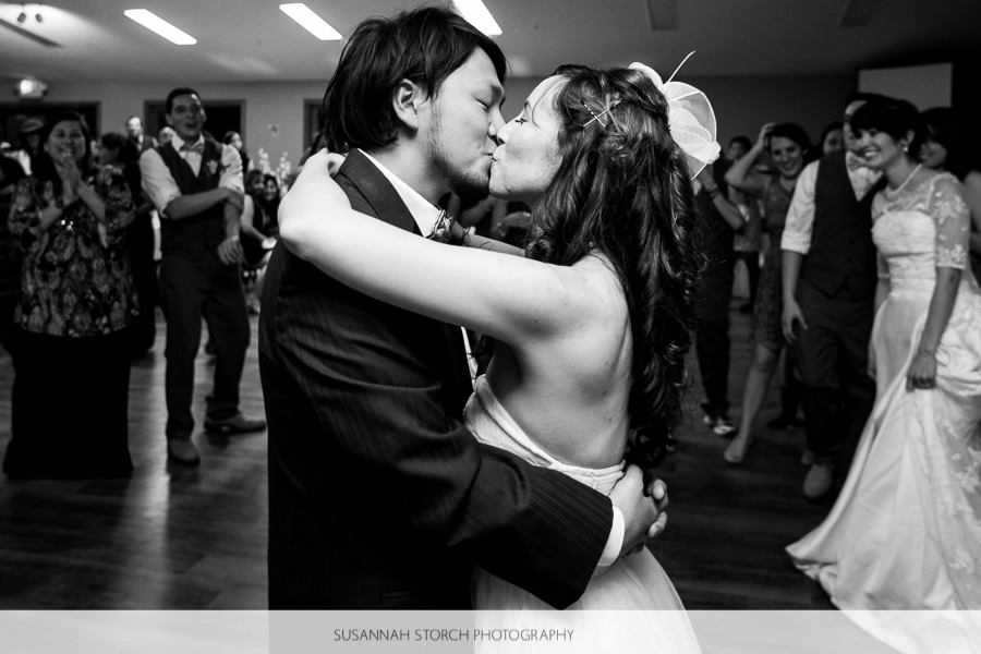 black and white photo of a bride and groom kissing on the dance floor