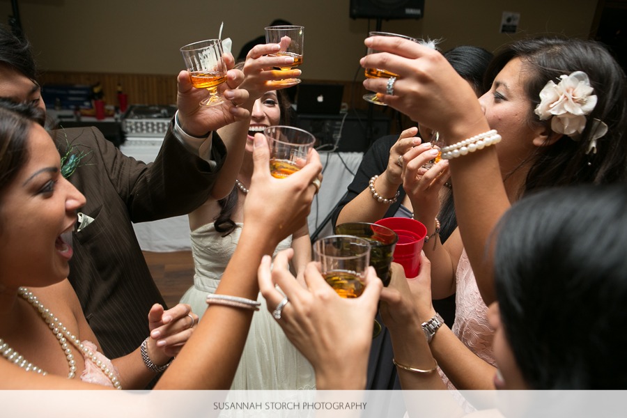 a group of well-dressed men and women raise shotglasses together