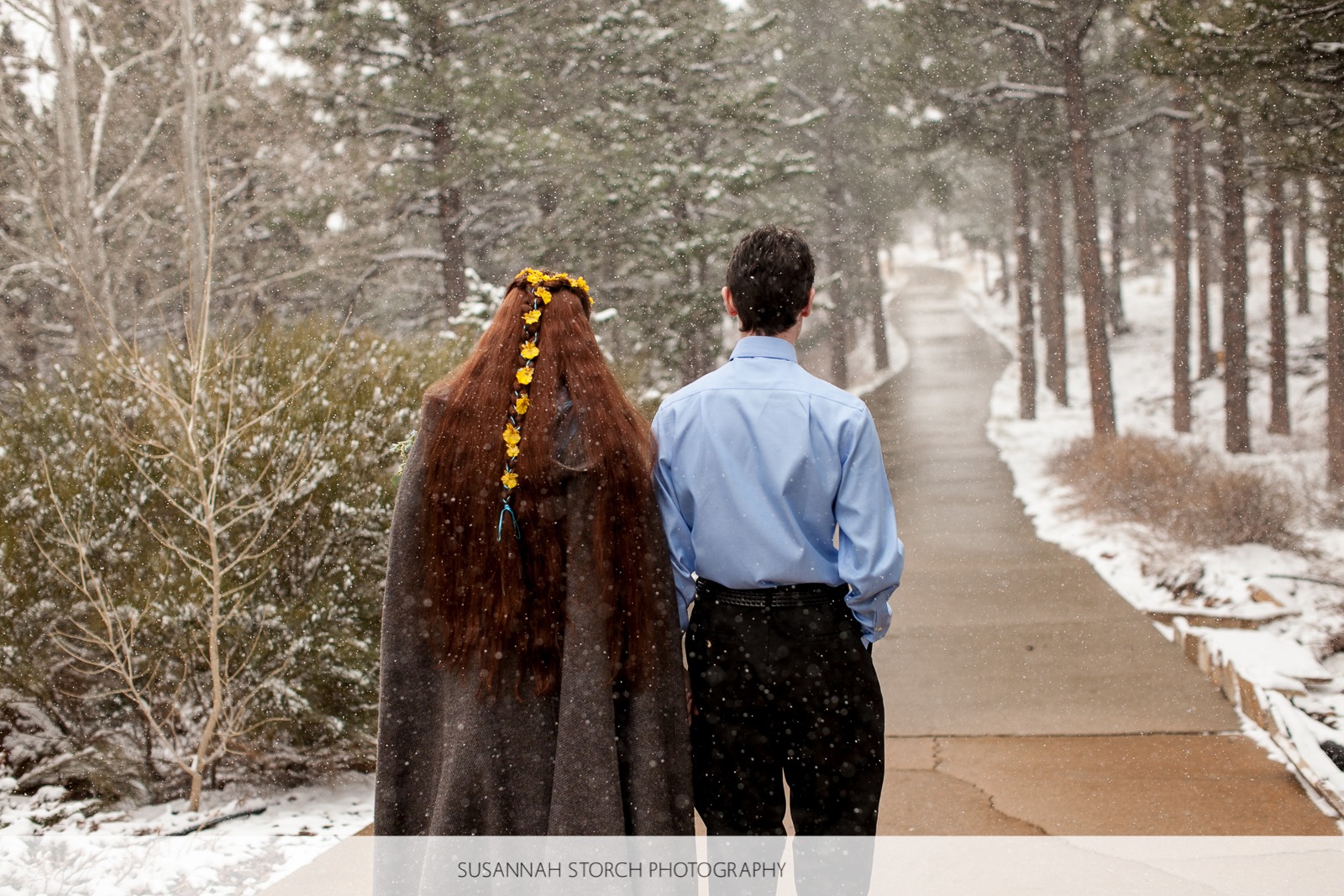 a woman with flowers in her hair walks down a concrete path in the snow