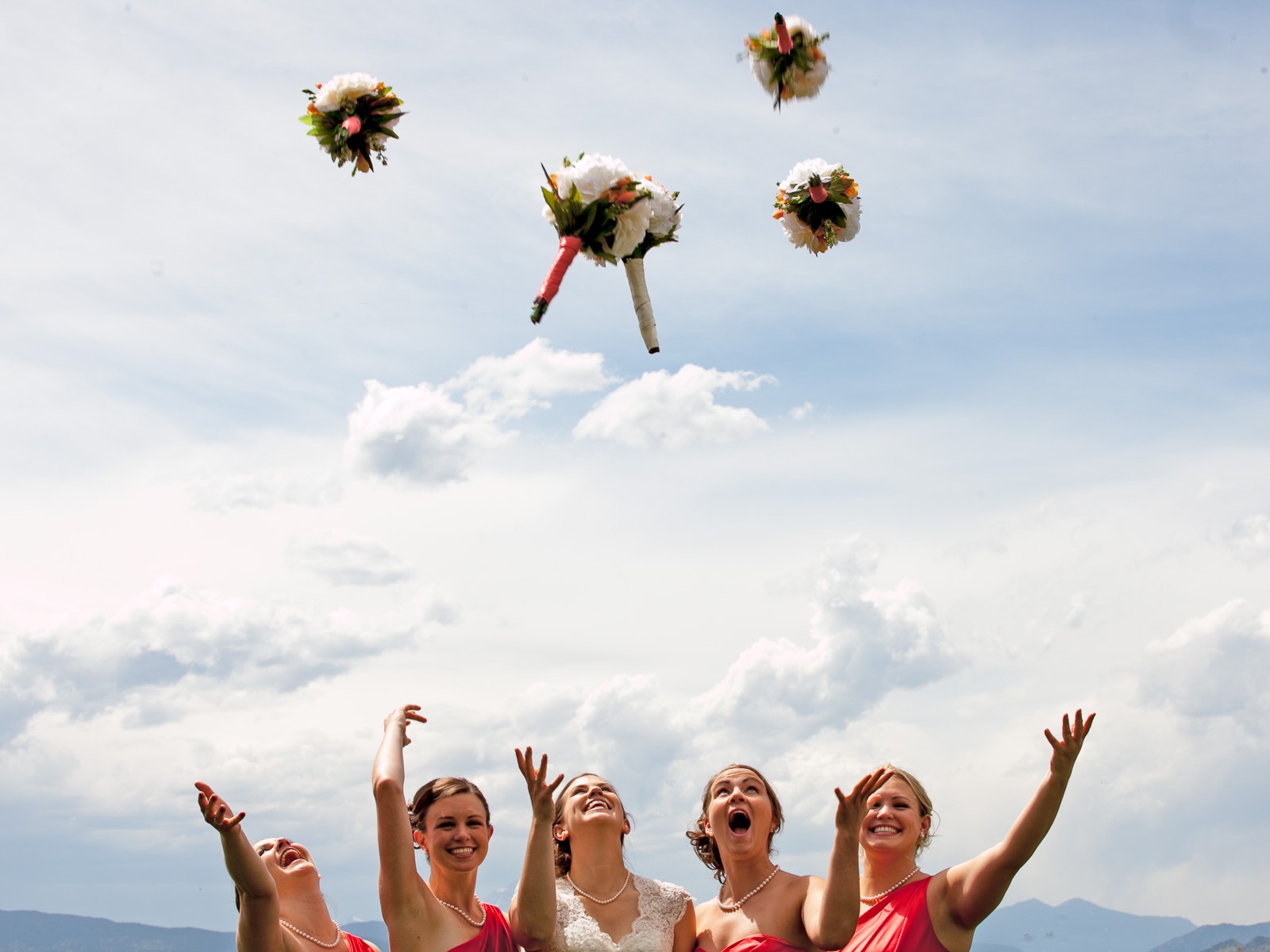 bride and bridesmaids throw bouquets into the air
