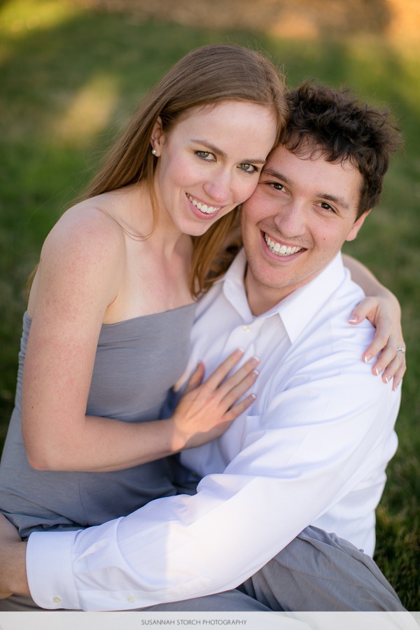 a woman sits on a man's lap in the grass