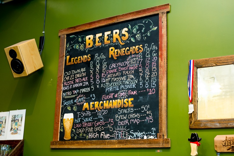 a beer menu on a chalkboard that hangs on a green wall