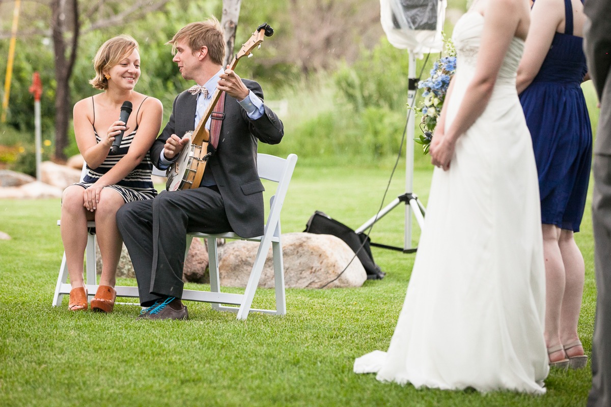 man plays the banjo and woman sings during an outdoor wedding ceremony