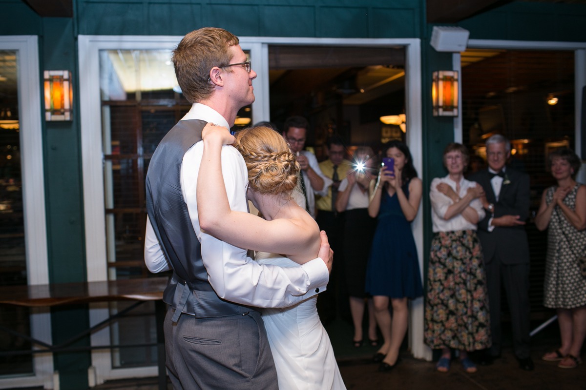 a bride and groom slowdance in a green room while people watch