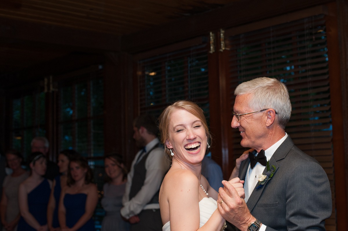 a bride smiles as her dad looks at her during the father-daughter dance