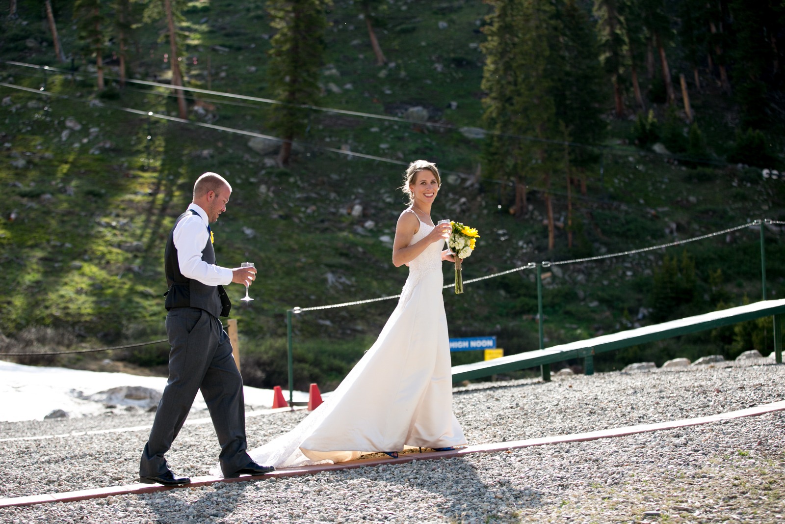 a groom walks behind a bride who is carrying a bouquet