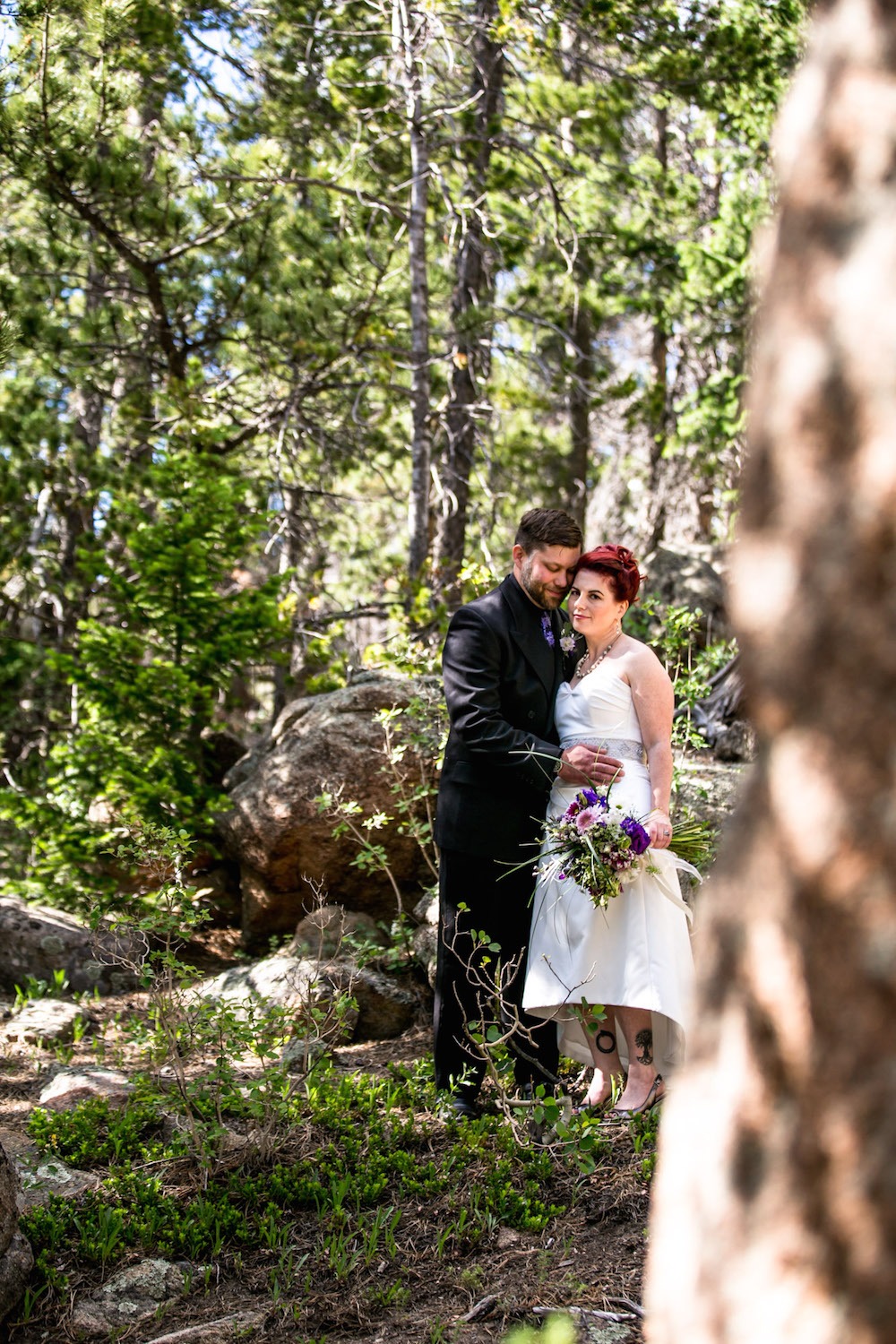 bride and groom stand up a hill in the woods