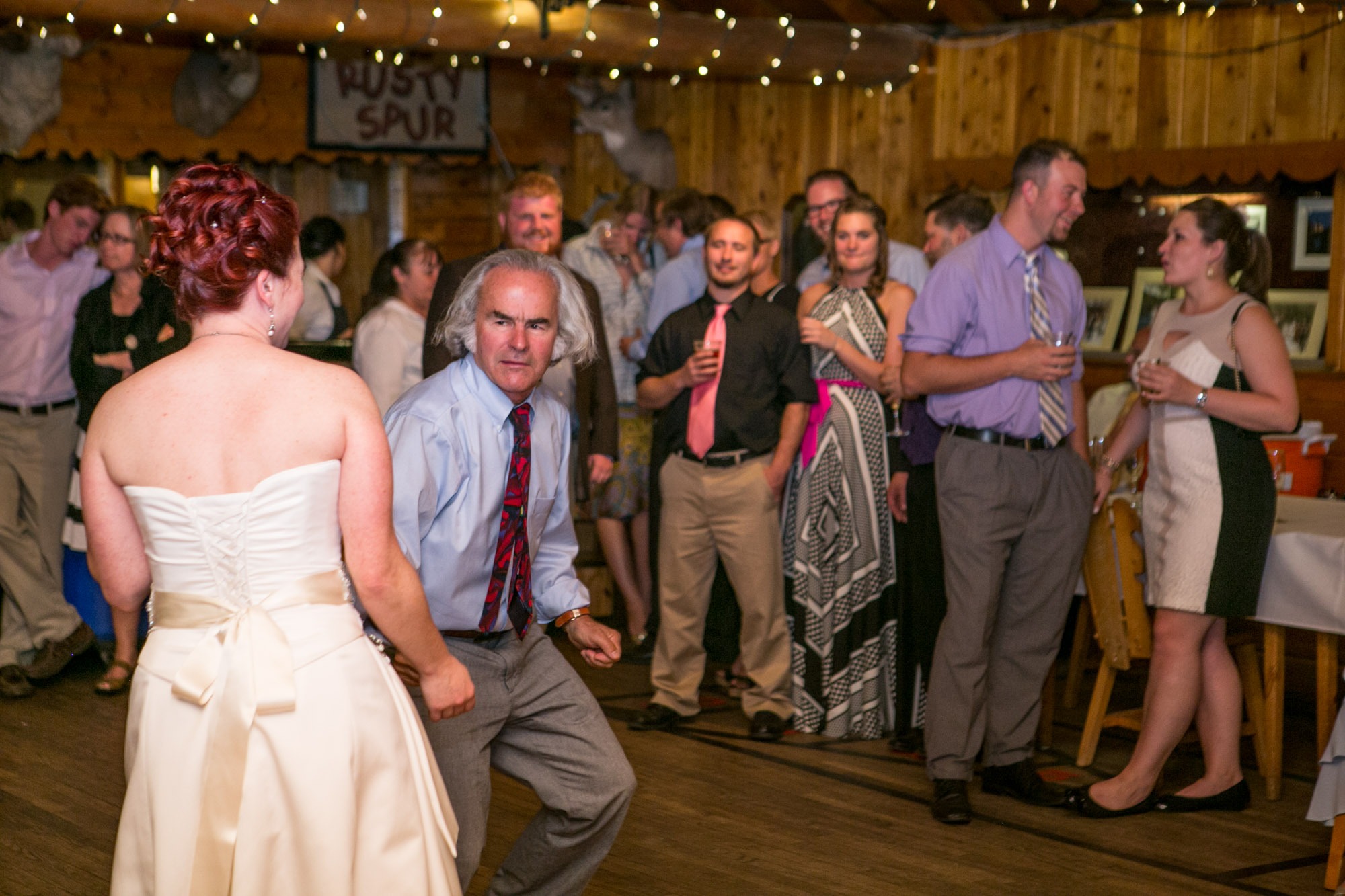a father dances with his daughter the bride as wedding guests watch