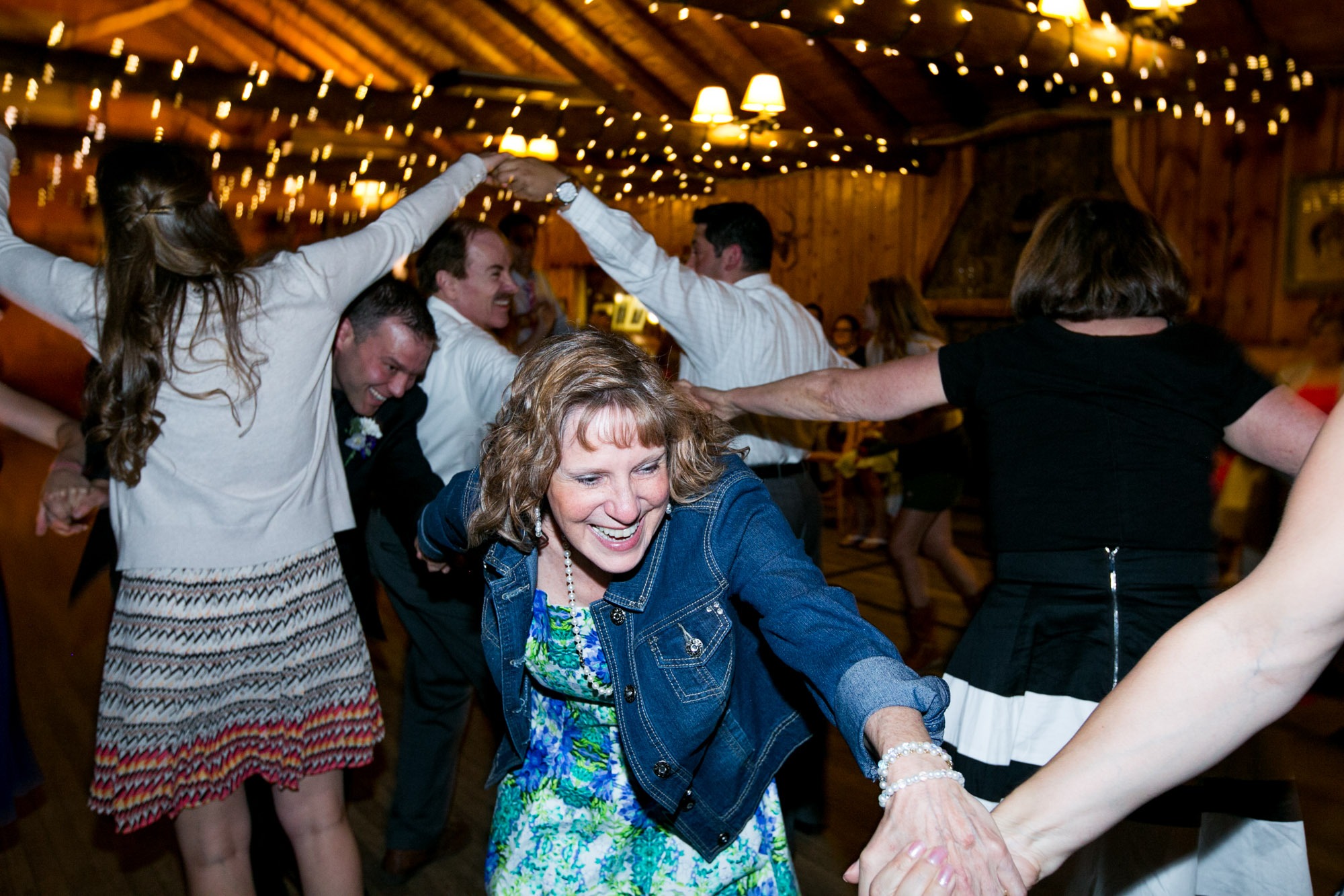 wedding guest hold hands and smile as they weave under hand tunnels while dancing