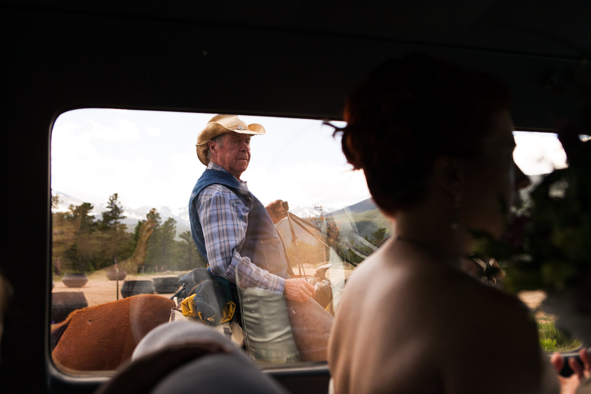a man on a horse rides next to a car carrying a woman in a strapless dress