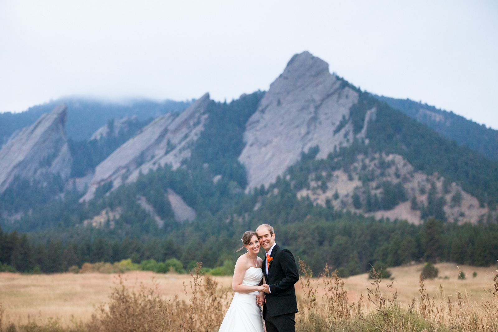 a bride and groom pose for a portrait in front of Boulder's iconic Flatirons