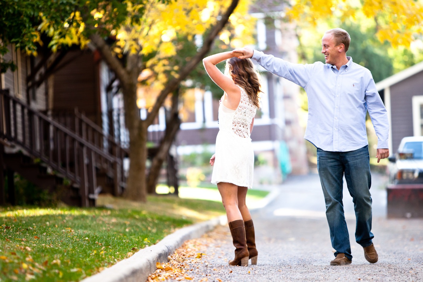 a man dances with a woman in a dress while walking down a suburban street