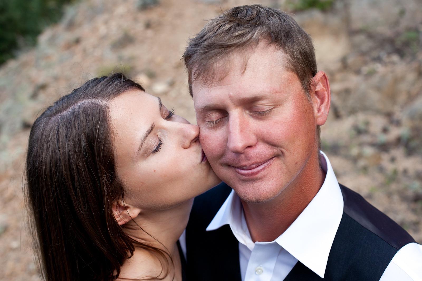 A woman kisses a man on the cheek