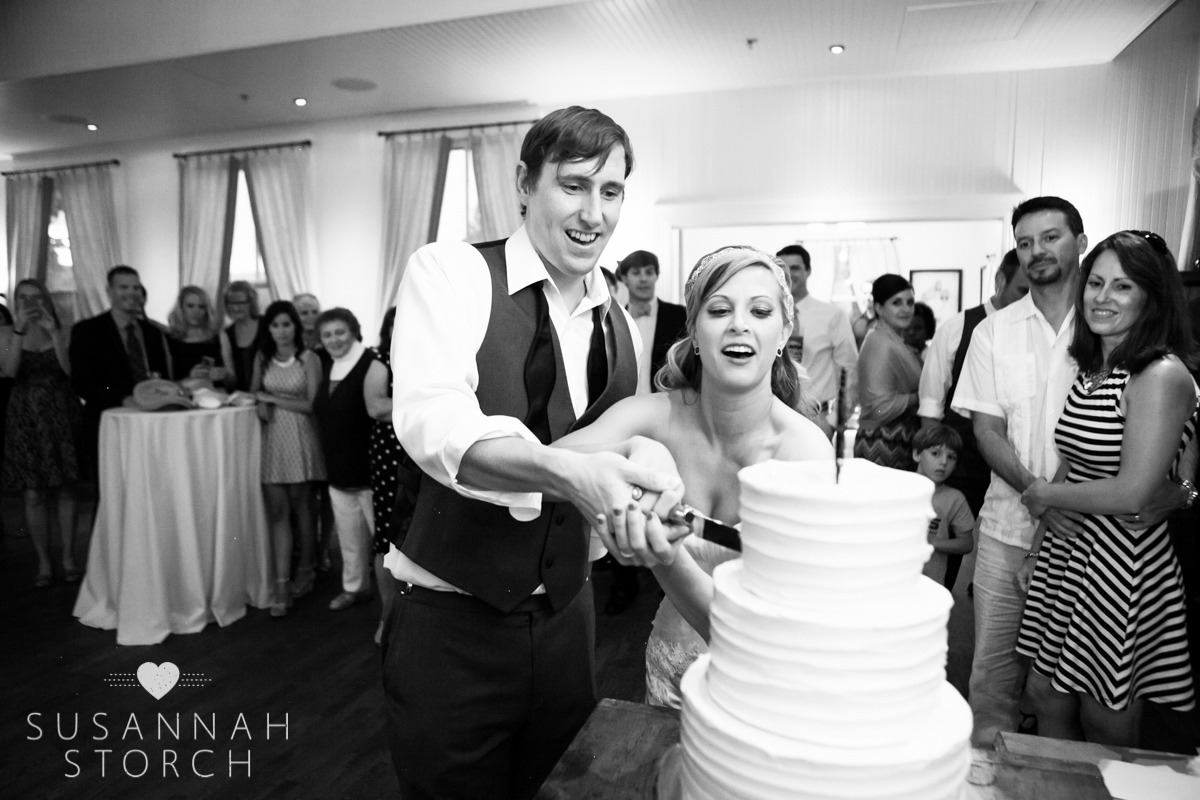 black and white photo of a bride and groom cutting a wedding cake