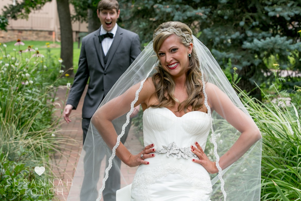 a bride smiles while a groom walks up behind her