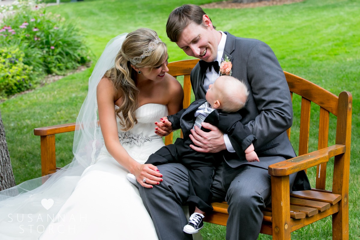 a bride and groom dote over a cute babt