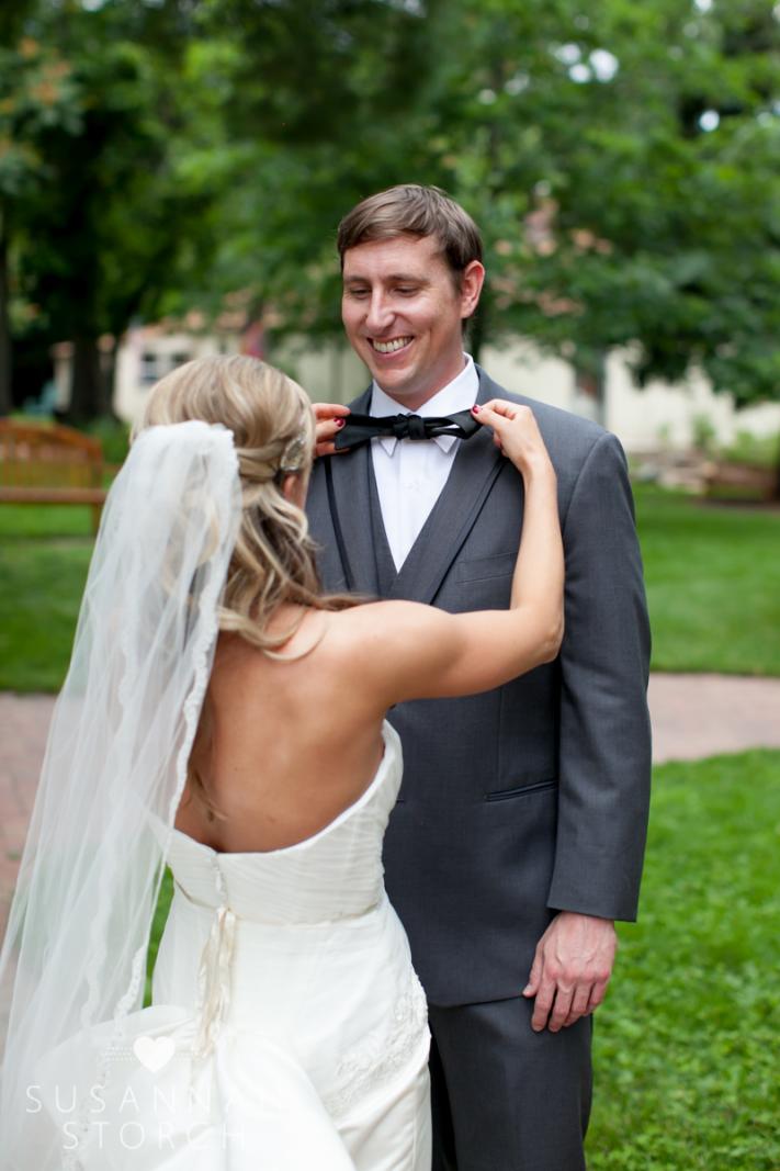 a bride tries to tie a black bow tie
