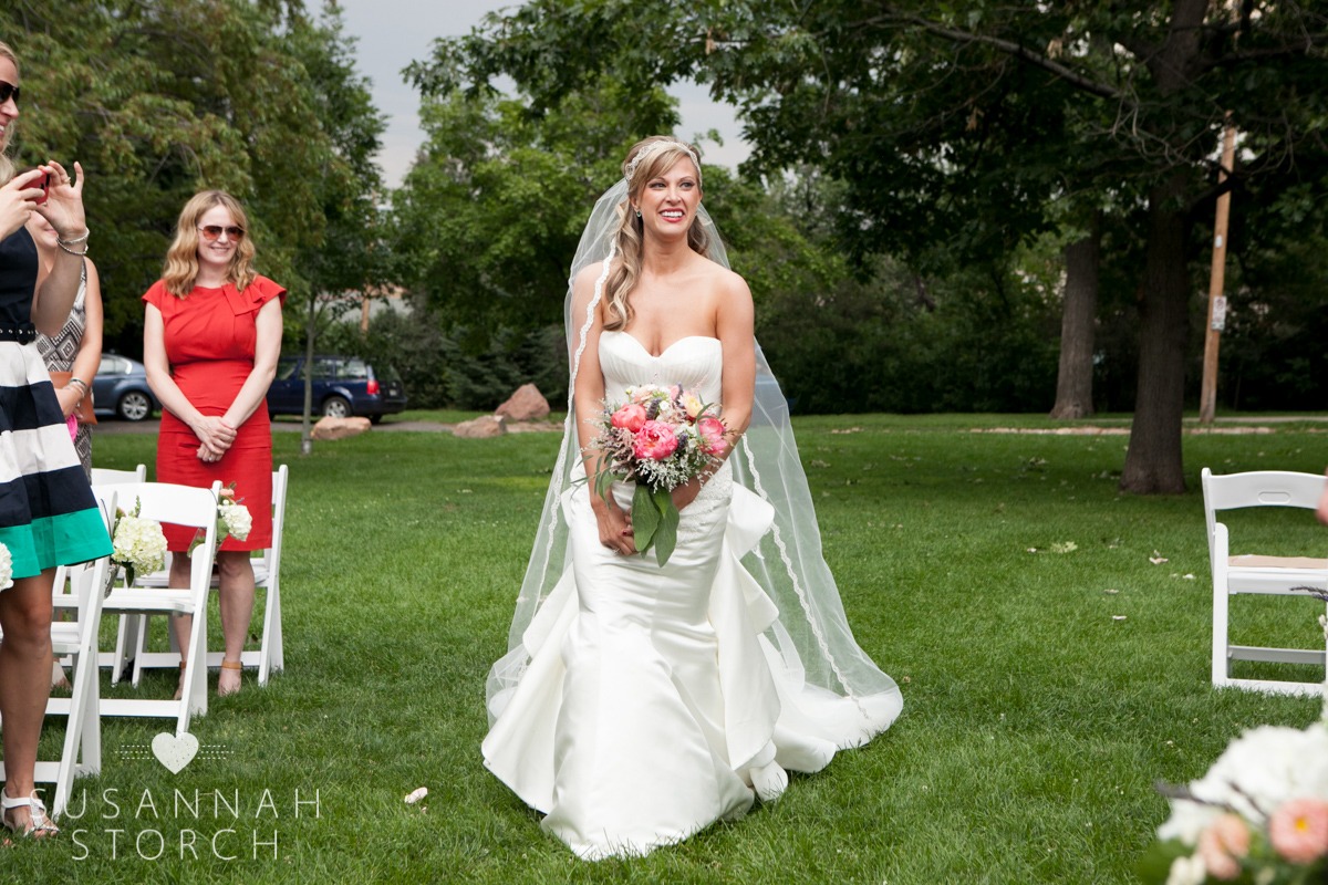 a happy bride walks down the green grass aisle
