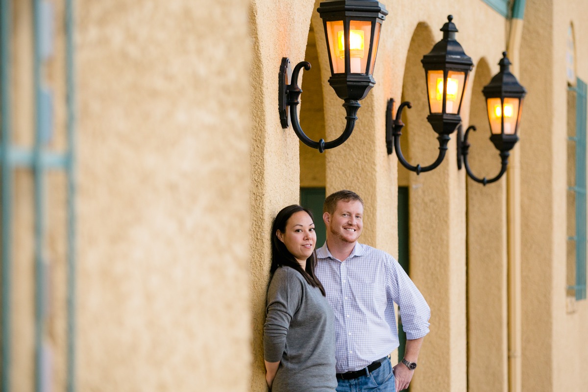 man and woman lean against stucco wall