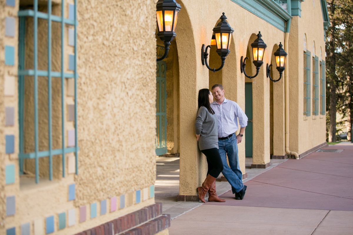 man and woman lean against a stucco building and chat