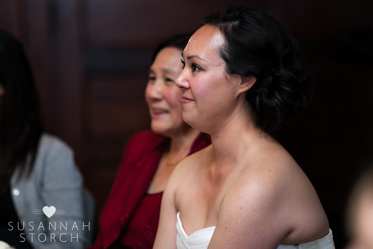 a bride and her mom smile while listening to wedding toasts