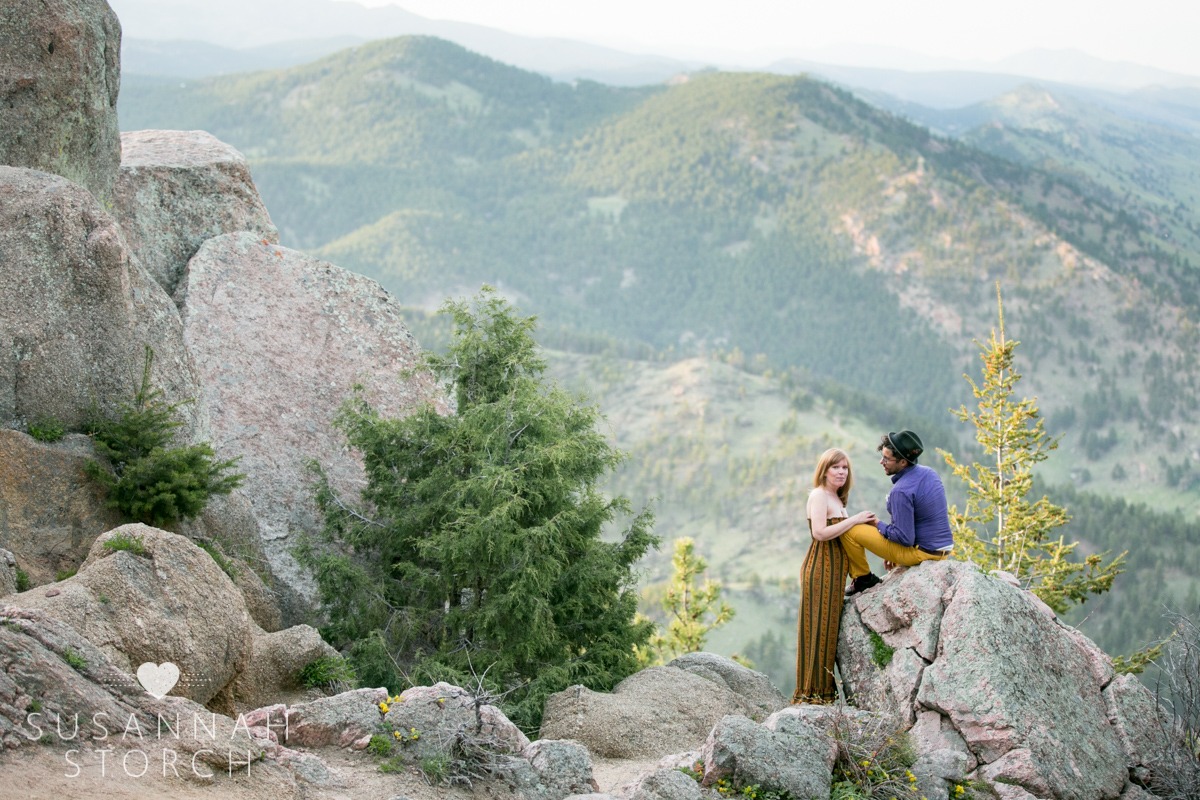 a man sitting on rocks and a woman looking at the camera in front of Boulder's mountains