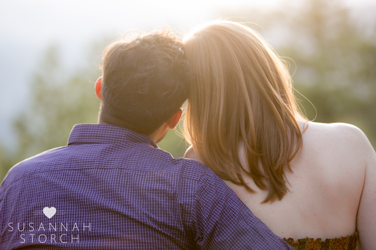 a man and woman touch heads as they look out at a beauitful sunset