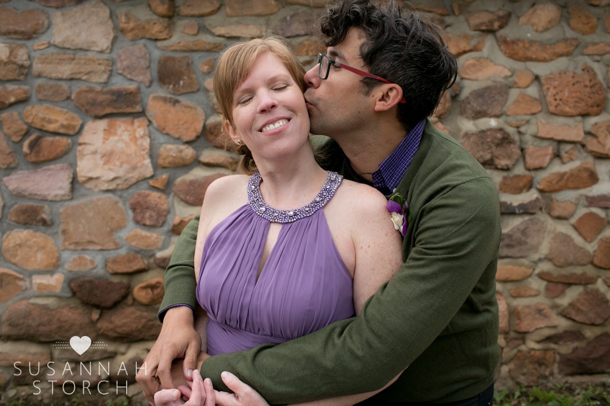 a groom kisses his bride who wears a purple dress
