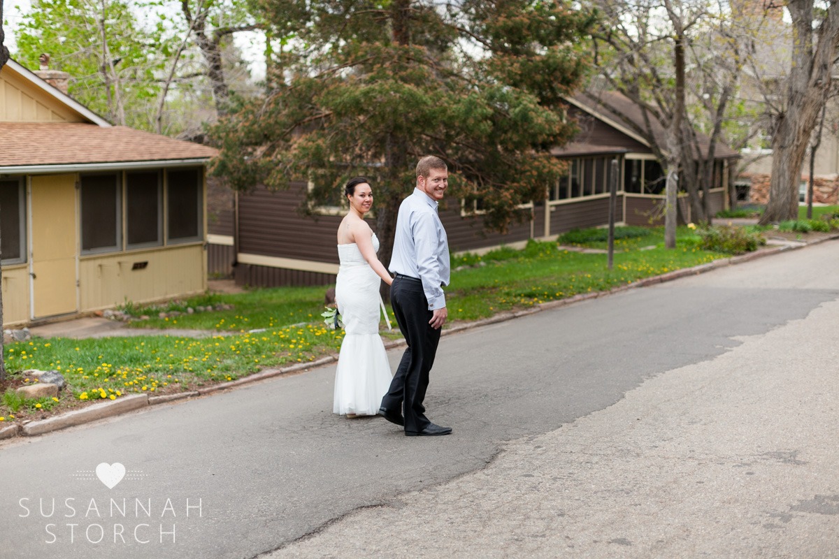 a wedding couple hold hands and walk by cabins