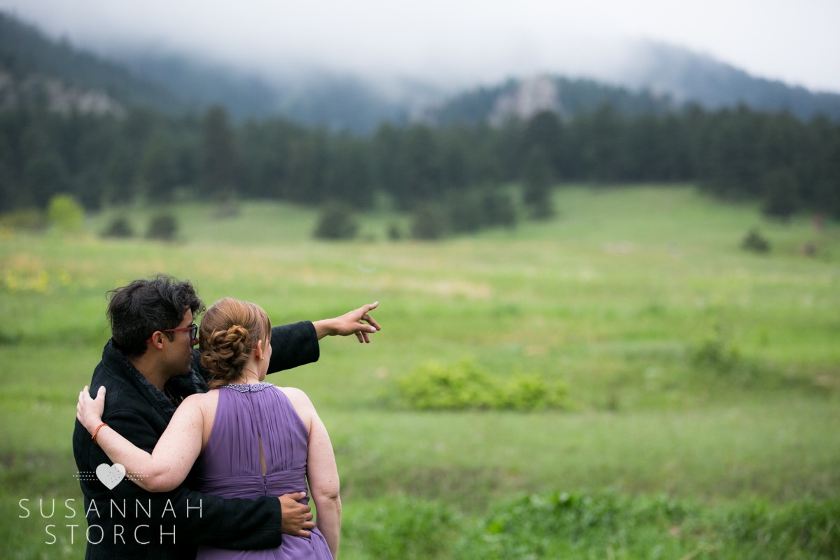 a groom points off into the cloudy mountains
