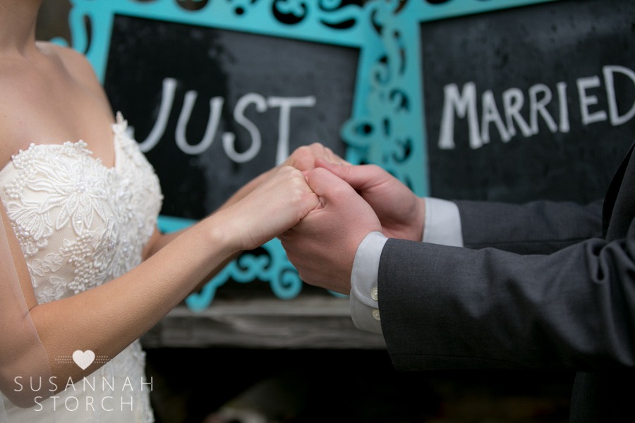 wedding couple hold hands in front of a sign that says Just Married