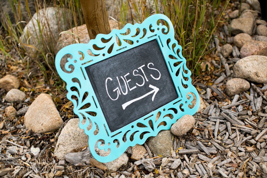 a turquoise chalkboard points guests to a wedding ceremony site