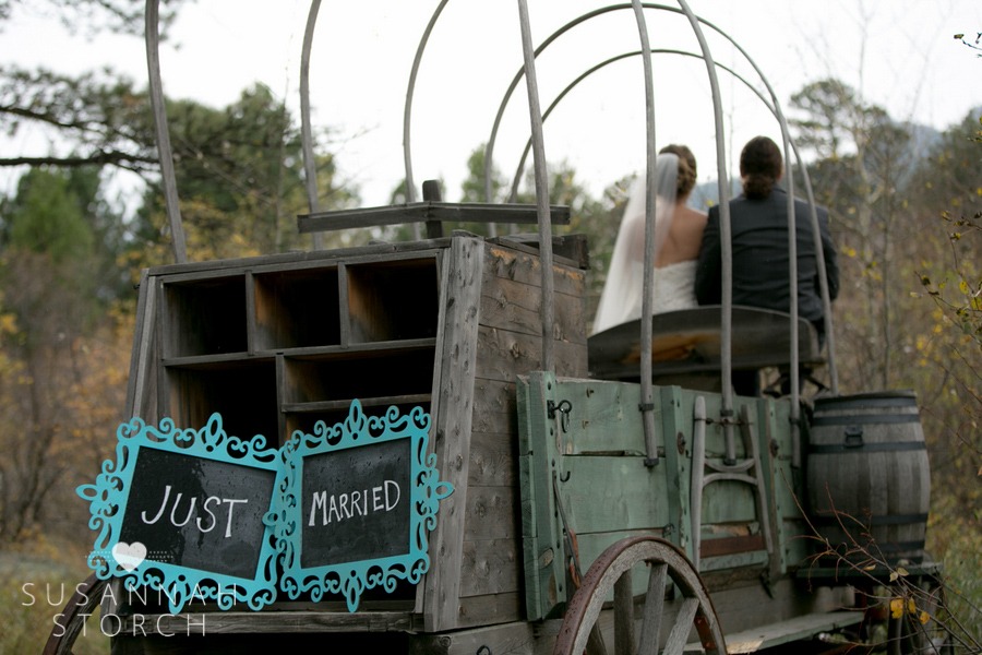 a bride and groom sit on old wagon
