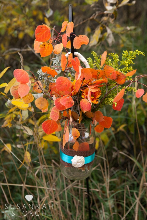 a mason jar of orange aspens leads guests to an outdoor ceremony site
