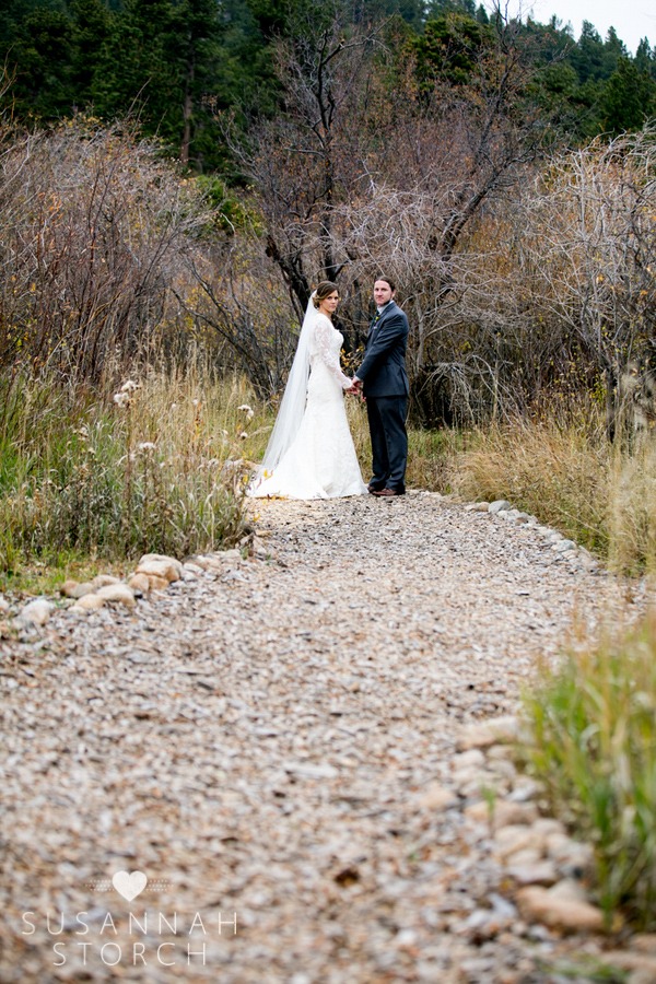 bride and groom hold hands on a mulch path
