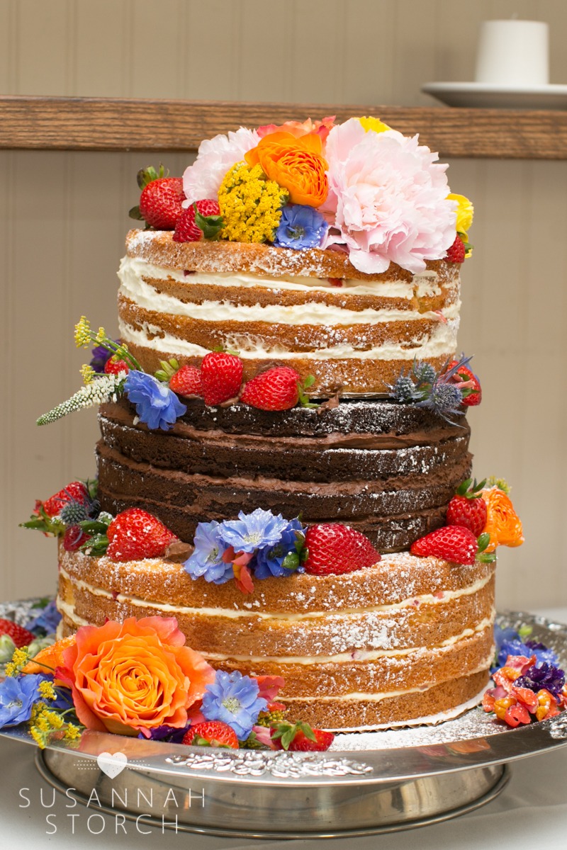 wedding cake gently covered with berries and flowers