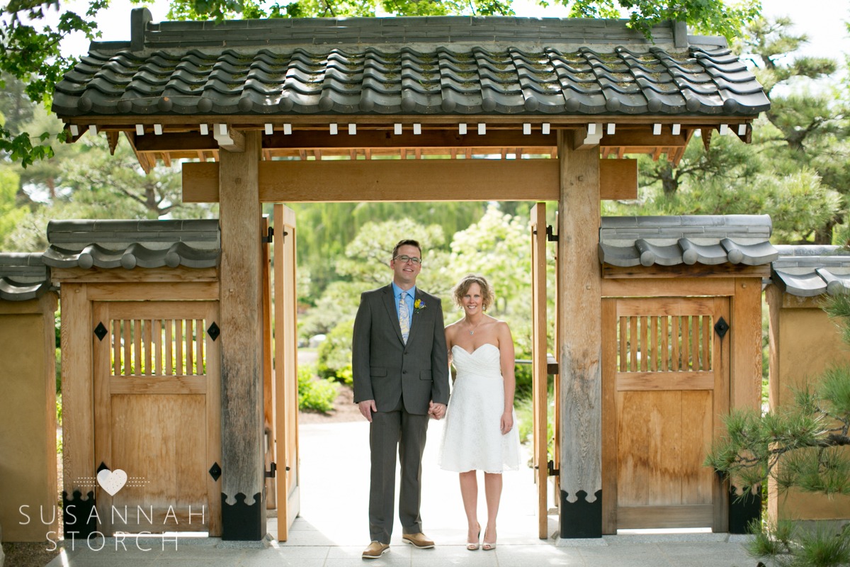 a bride and groom hold hands in front of a Japanese-looking gate at the Denver Botanic Gardens